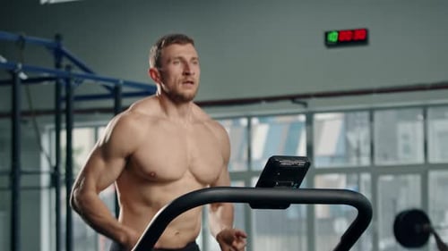 Shirtless Man Runs on Treadmill in Gym