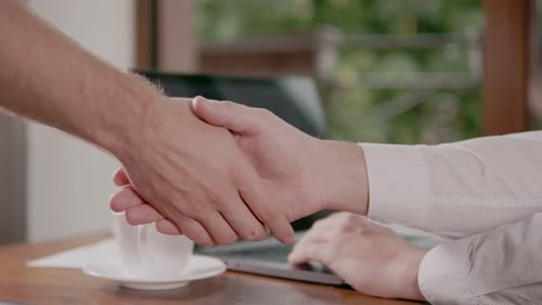Business Handshake Over Desk with Laptop and Coffee