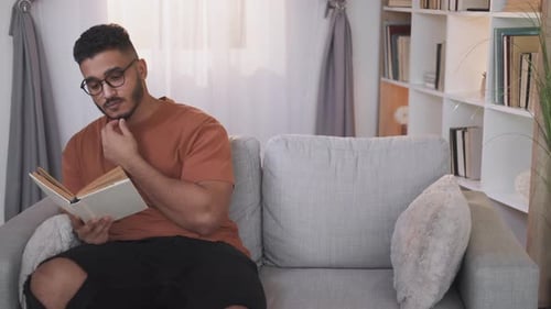 Young Adult Reading Book Indoors on Couch