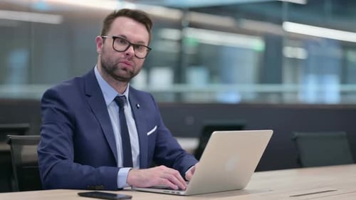 Man in Suit Typing on Laptop in Office