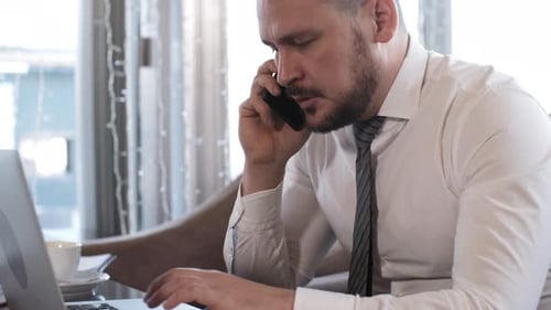 Professional Man Talking on Phone While Using Laptop