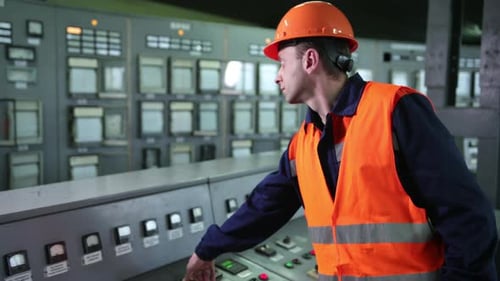 Worker Pressing Buttons on CNC Machine Control Board in Factory