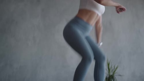 Athletic Woman Jumps on a Trampoline Indoors