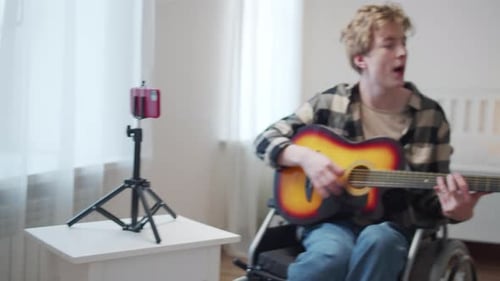 Young Adult Sings and Plays Guitar in Bedroom