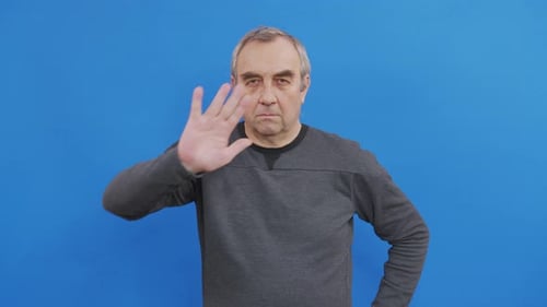 Man Gesturing Stop with Hand in Front of Blue
