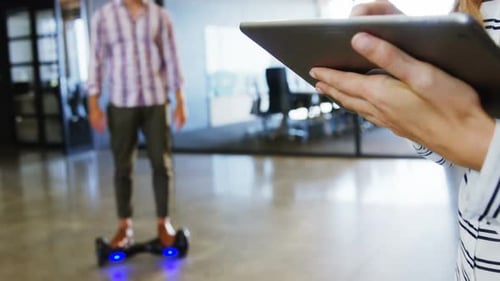 Homme en hoverboard utilisant une tablette numérique avec des collègues