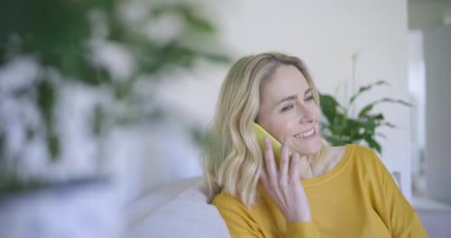 Mature woman sitting on couch chatting on the phone