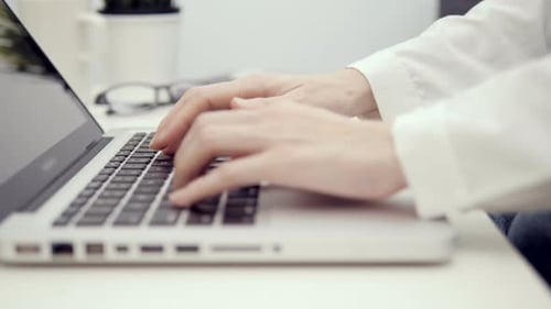 Hands Typing on Laptop Keyboard in Office