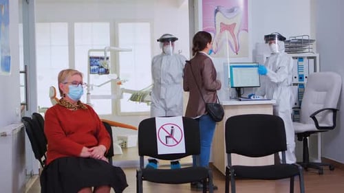 Dental Doctor in Protective Suit Working in Busy Stomatological Clinic