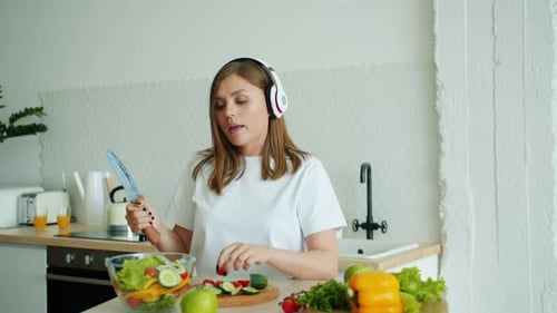 Woman Enjoys Making Salad and Dancing in Kitchen
