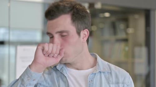 Portrait of Sick Young Male Designer Coughing in Office