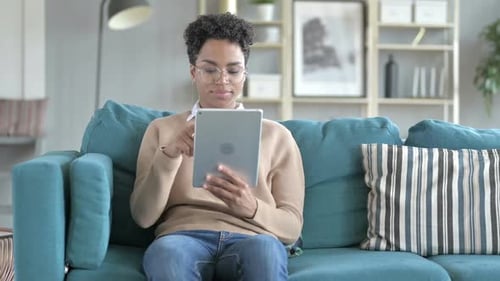 Woman using Tablet on Couch Indoors During Daytime