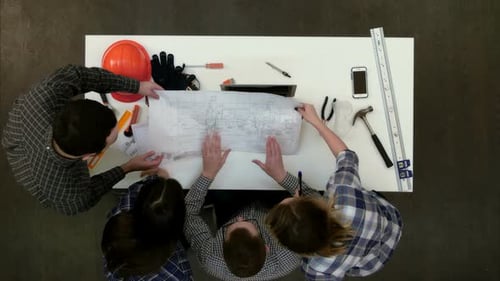 Architektengruppe diskutiert technische Zeichnungen
