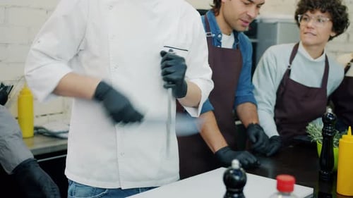 Male Chef Sharpening Knife in Kitchen During Master-class in Cookery School