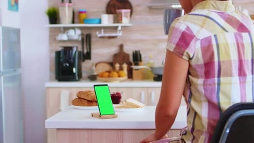 Housewife Looking at Mobile Phone with Green Screen Display