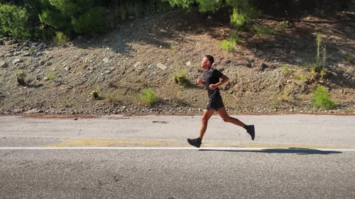 Man Running on Roadside in Daytime