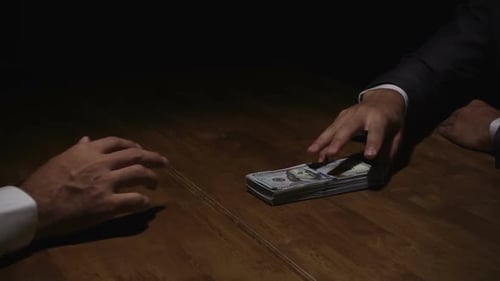 Businessman rejecting money offered by his partner in the dark - anti bribery concept