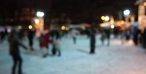 People Ice Skating at Night on an Ice Rink