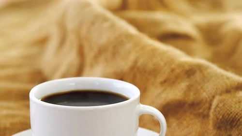 White Mug of Steaming Black Coffee on Tabletop