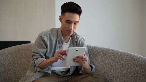 Young Adult Using Tablet on Modern Couch
