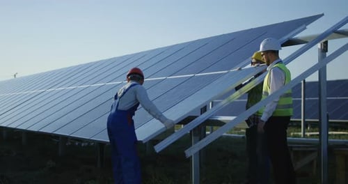 Drei Arbeiter installieren ein Solarpanel