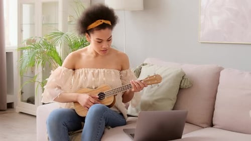 Woman Plays Ukulele on Couch at Home