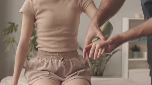 Therapist Treating Young Woman's Arm in Clinic