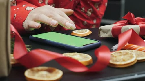 Smartphone with green screen on background of Christmas tree and holiday lights