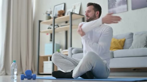 Man Stretching Arms on Yoga Mat at Home