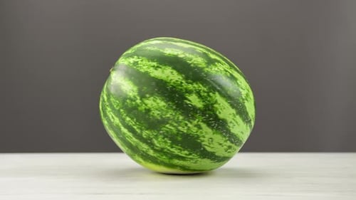 Appetitliche frische Wassermelone, rotierend auf einem Holztisch, isoliertes Sommer-Vitamin-Dessert