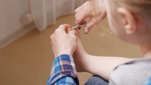 Adult Carefully Trims Child's Toenails with Scissors