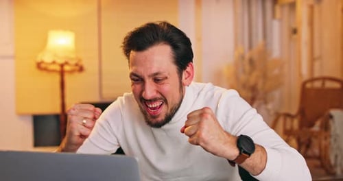 Excited Man Celebrates Success at Laptop