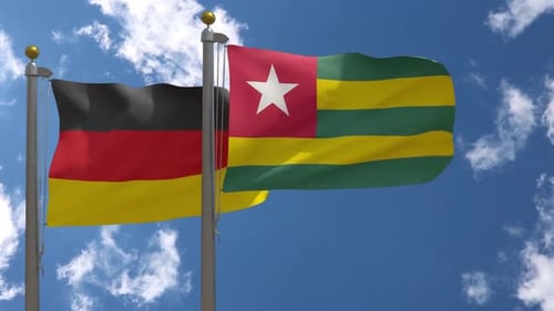 Waving Flags of Germany and Togo Against Blue Sky