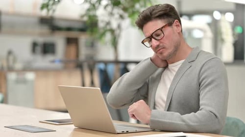 Middle Aged Man with Laptop Having Neck Pain in Office