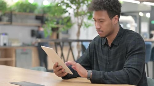 Attraktiver Afroamerikaner mit Tablet bei der Arbeit