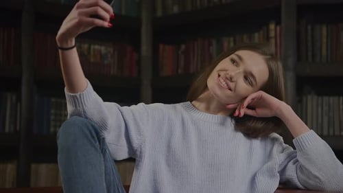 Smiling Woman Posing for Selfie in Front of Bookshelf