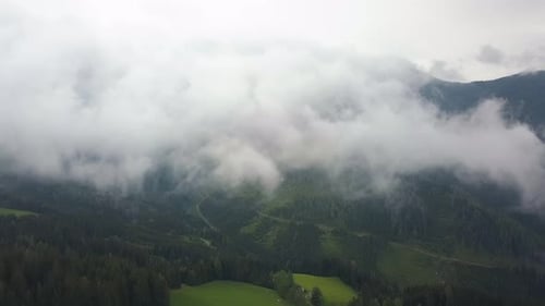 Luftaufnahme in Wolken, Kamera über grünen Bergen und Feldern