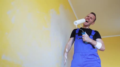 Professional young happy man with paint roller having fun