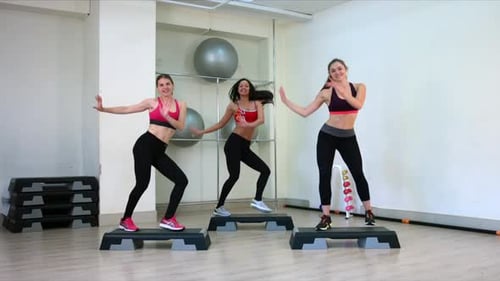 Women Practicing Step Aerobics in Fitness Studio