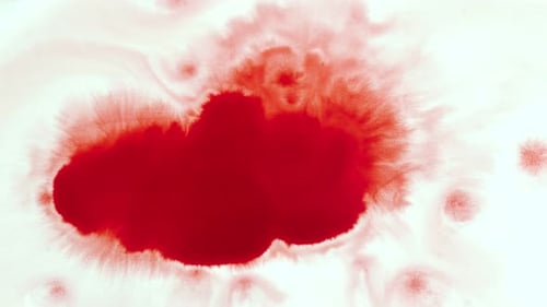 Red Ink Spreads across White Surface