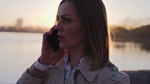 Woman Talking on Phone at Sunset by Water