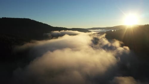 Aerial View of a Misty Lake. Dawn Dark Lights During Sunrise, Cold Weather. Flying Over Clouds in th