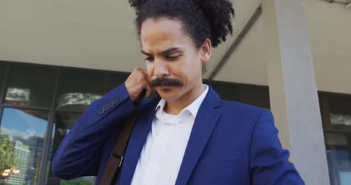 Mixed race man with moustache walking on the street and using smartphone