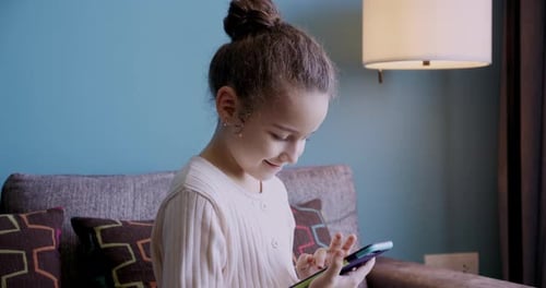 Girl Using a Mobile Phone Sitting on Sofa