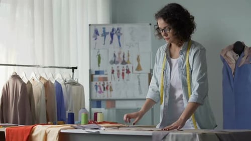 Smiling Designer Looking at Patterns and Planning Their Placement on Fabric