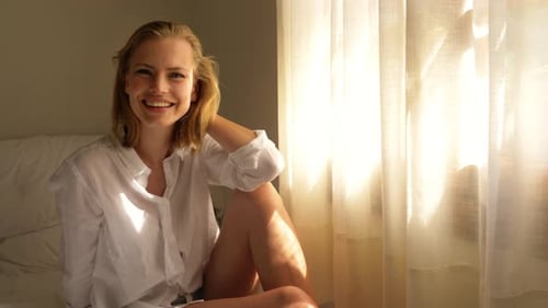 Bela modelo com seus pensamentos vagando pela cama perto do peitoril da janela