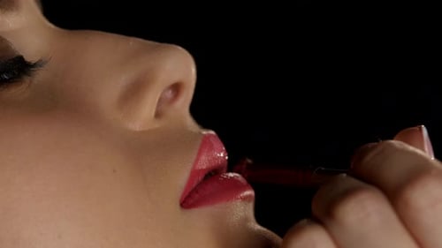 Maskenbildnerin arbeitet an einer Schönheit für junge Mädchen. Lippenfarbe Lippenstift. Schwarz. Nahaufnahme