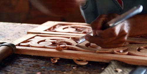 Skilled Artisan Carving Intricate Design Into Wood Panel