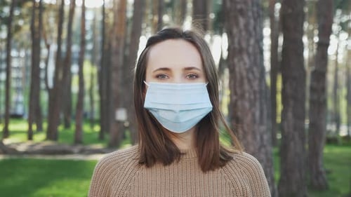 Portrait of young european girl wearing protective medical face mask on the street.
