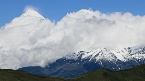 Timelapse Clouds Swirl Over a Mountain Valley a Snowy Peak in the Distance